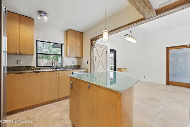 kitchen featuring a center island, dark stone counters, light tile patterned floors, hanging light fixtures, and a sink