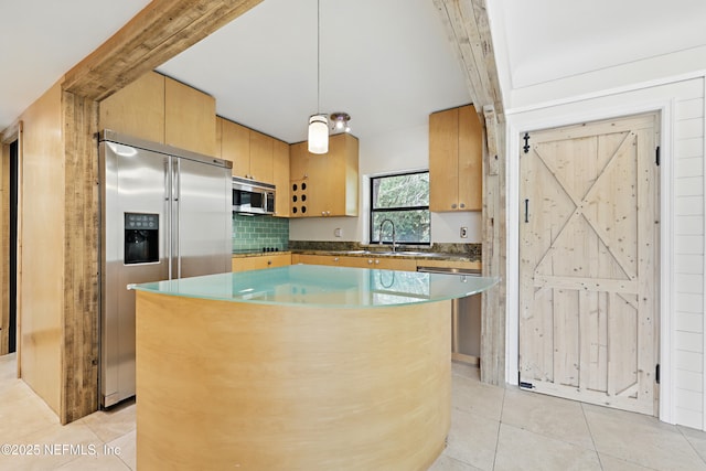 kitchen featuring light brown cabinets, a sink, a kitchen island, appliances with stainless steel finishes, and light tile patterned flooring