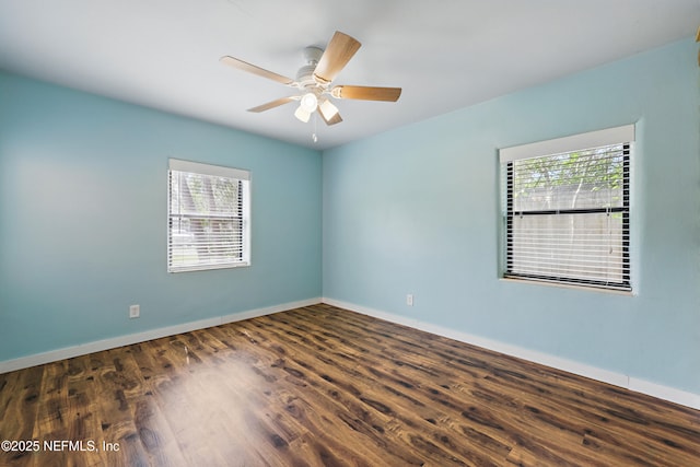 spare room featuring baseboards, wood finished floors, and a ceiling fan