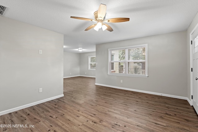 interior space with a ceiling fan, wood finished floors, visible vents, baseboards, and a textured ceiling