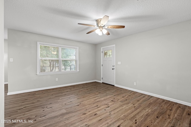 foyer entrance with a ceiling fan, wood finished floors, baseboards, and a textured ceiling