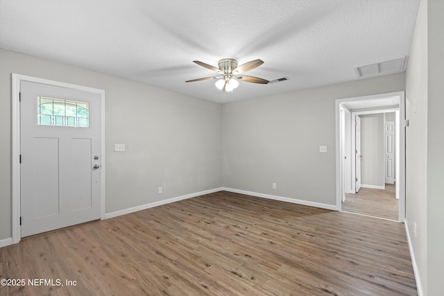 foyer entrance with visible vents, a textured ceiling, ceiling fan, and wood finished floors