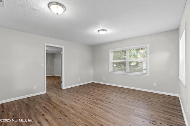 spare room featuring wood finished floors, baseboards, and a textured ceiling