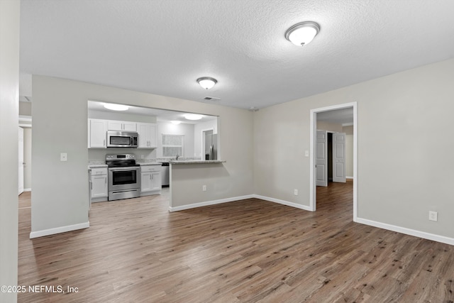 kitchen featuring stainless steel appliances, light wood-style floors, visible vents, and white cabinets