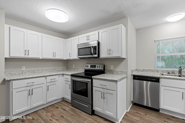 kitchen featuring wood finished floors, stainless steel appliances, light countertops, and a sink