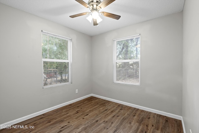 spare room with baseboards, a textured ceiling, dark wood finished floors, and a ceiling fan