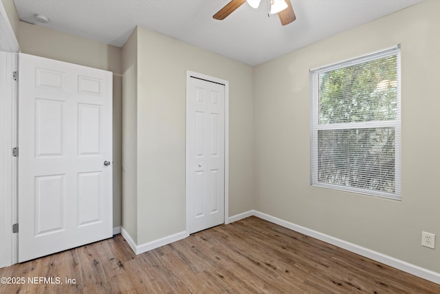 unfurnished bedroom with ceiling fan, wood finished floors, a closet, and baseboards