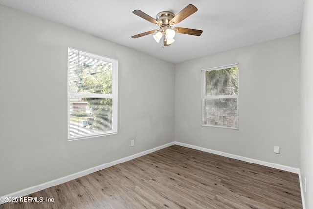 empty room with baseboards, wood finished floors, and a ceiling fan