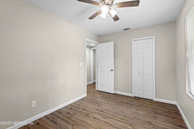 unfurnished bedroom with visible vents, baseboards, and wood finished floors