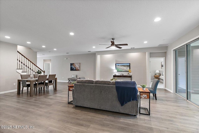 living room with recessed lighting, stairway, a textured ceiling, and light wood finished floors