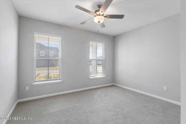 carpeted spare room with baseboards and ceiling fan