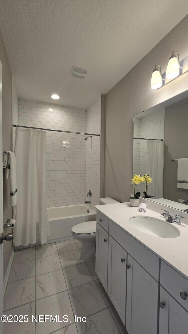 bathroom featuring vanity, shower / bath combo with shower curtain, a textured ceiling, toilet, and marble finish floor