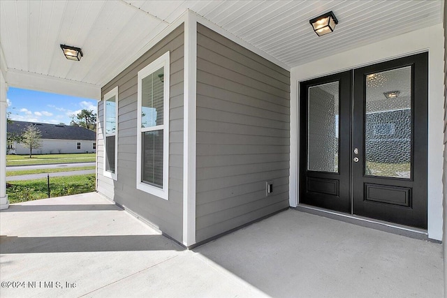 view of exterior entry featuring a porch and french doors