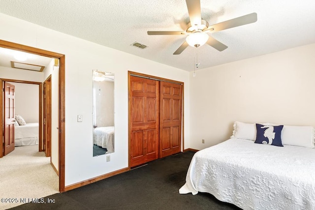 carpeted bedroom featuring visible vents, a ceiling fan, a textured ceiling, a closet, and attic access