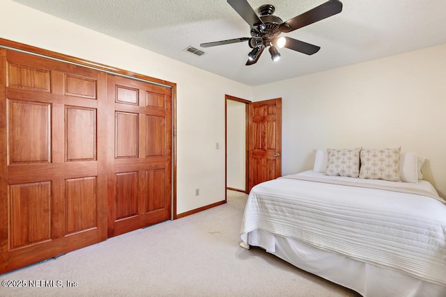 bedroom with visible vents, baseboards, ceiling fan, light colored carpet, and a textured ceiling