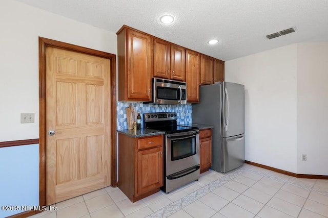 kitchen featuring brown cabinetry, visible vents, backsplash, and stainless steel appliances