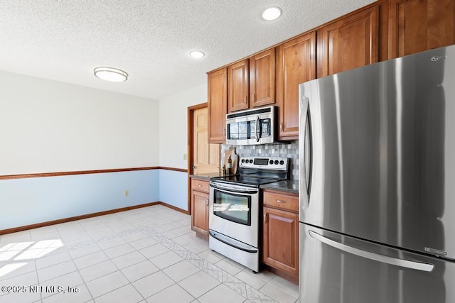 kitchen with decorative backsplash, brown cabinetry, appliances with stainless steel finishes, and a textured ceiling