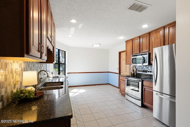 kitchen featuring visible vents, brown cabinets, backsplash, stainless steel appliances, and light tile patterned floors