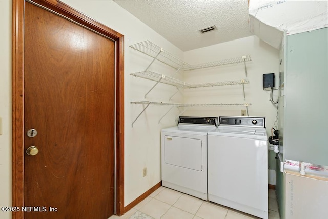 washroom with light tile patterned floors, baseboards, laundry area, a textured ceiling, and washer and dryer