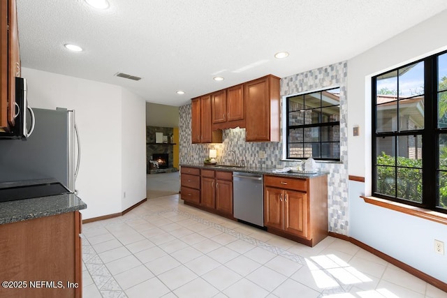 kitchen with visible vents, backsplash, brown cabinetry, stainless steel appliances, and a sink