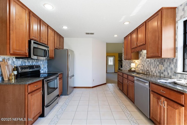 kitchen featuring baseboards, visible vents, light tile patterned flooring, a sink, and appliances with stainless steel finishes