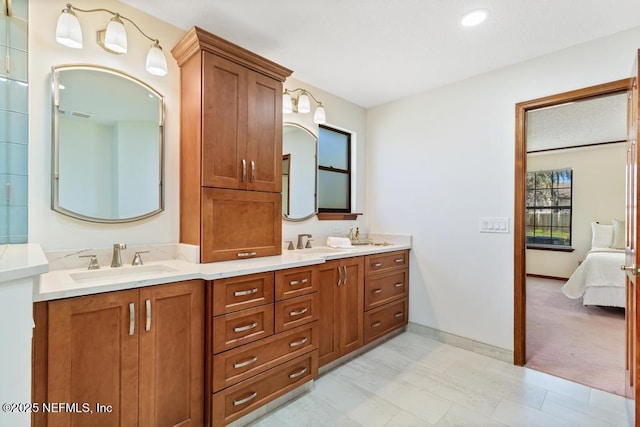 ensuite bathroom featuring a sink, connected bathroom, baseboards, and double vanity