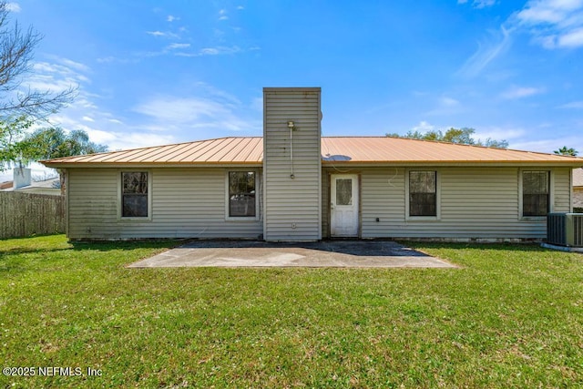 rear view of house featuring a patio area, central air condition unit, a chimney, and metal roof