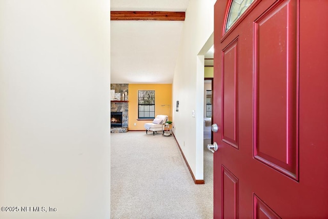 carpeted entryway with beamed ceiling, a fireplace, and baseboards