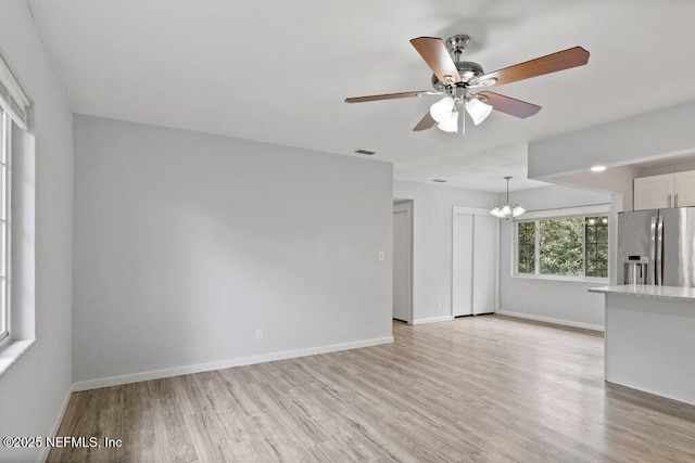 interior space with visible vents, baseboards, light wood-style flooring, and ceiling fan with notable chandelier