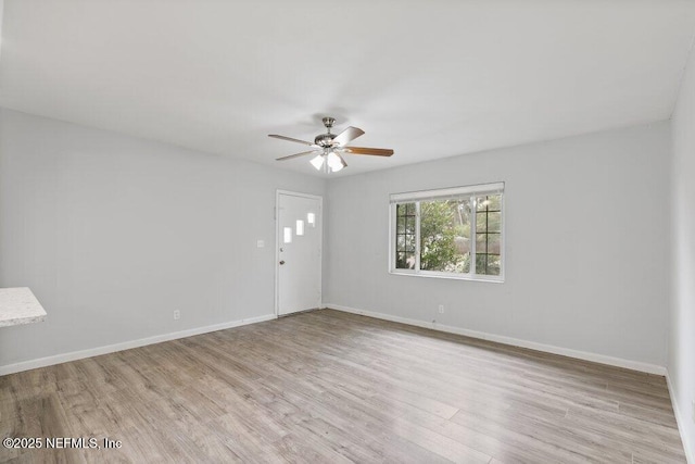 spare room featuring wood finished floors, baseboards, and ceiling fan