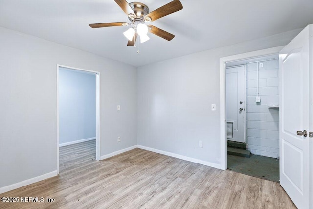 empty room with ceiling fan, light wood-type flooring, and baseboards