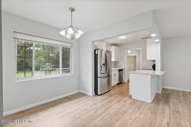 kitchen featuring baseboards, light wood finished floors, appliances with stainless steel finishes, white cabinetry, and backsplash