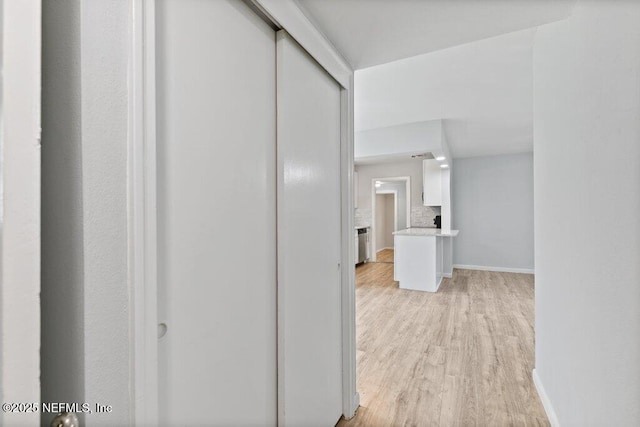 corridor with baseboards and light wood finished floors