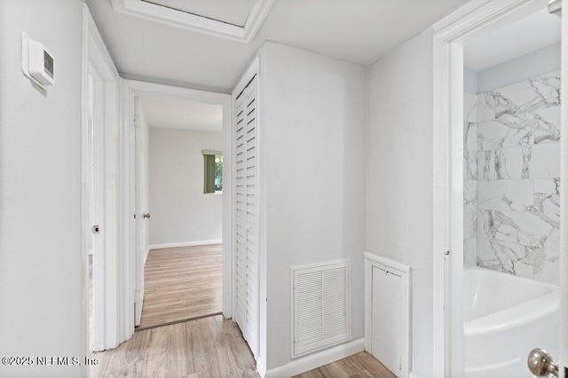 corridor with attic access, wood finished floors, visible vents, and baseboards