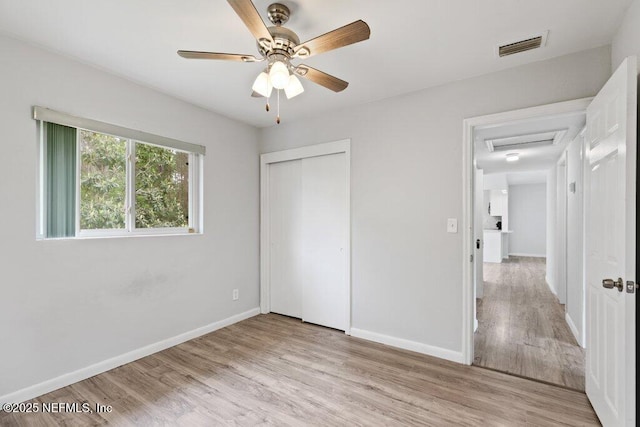 unfurnished bedroom featuring a closet, a ceiling fan, light wood-type flooring, and baseboards