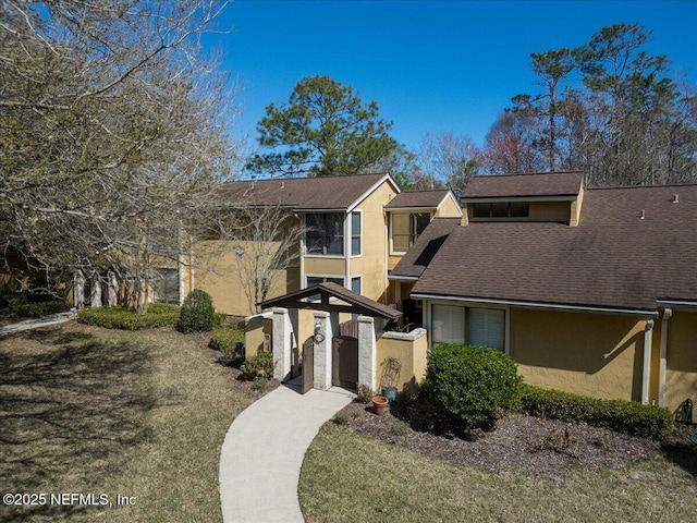 view of front of home featuring stucco siding, a shingled roof, a fenced front yard, and a gate