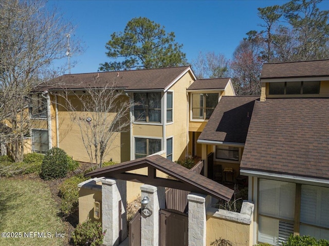 exterior space with stucco siding and roof with shingles