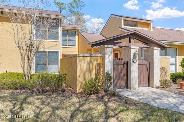 view of front of house with stucco siding and a gate