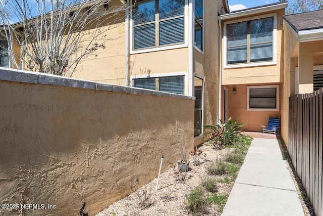 view of property exterior featuring stucco siding and fence