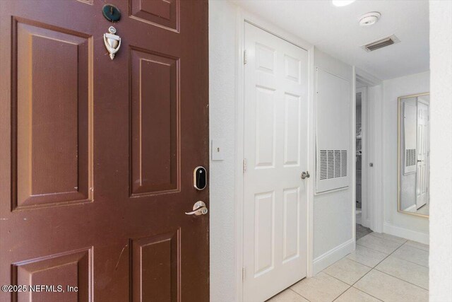 corridor with light tile patterned floors, visible vents, and baseboards