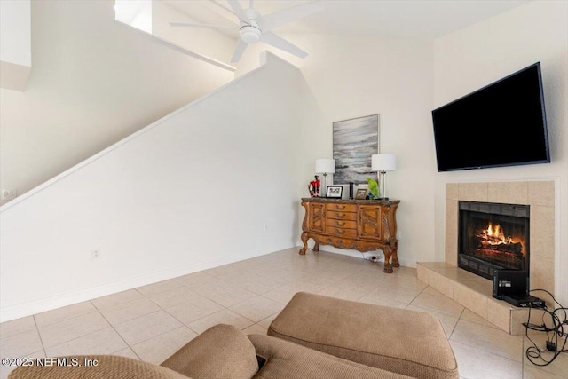 tiled living area featuring baseboards, lofted ceiling, ceiling fan, and a tile fireplace