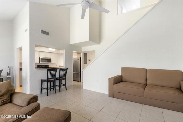 living area featuring light tile patterned floors, visible vents, baseboards, and a ceiling fan