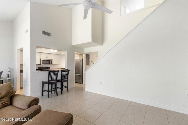 living room with visible vents, baseboards, light tile patterned flooring, and a ceiling fan