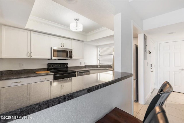 kitchen featuring ornamental molding, a sink, a tray ceiling, appliances with stainless steel finishes, and light tile patterned floors