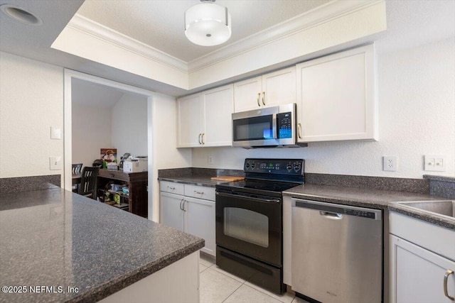 kitchen featuring dark countertops, white cabinetry, stainless steel appliances, and ornamental molding