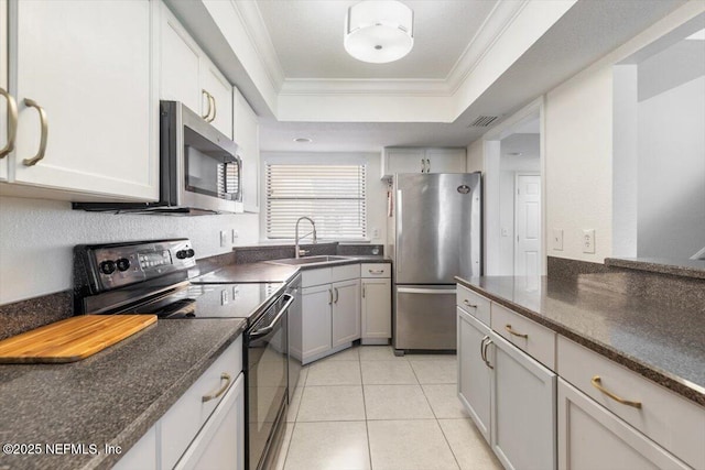 kitchen with light tile patterned floors, a tray ceiling, a sink, appliances with stainless steel finishes, and crown molding