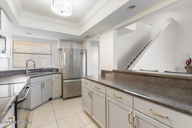 kitchen with crown molding, dark countertops, appliances with stainless steel finishes, and a sink