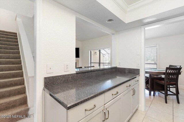 kitchen featuring white cabinetry, crown molding, and light tile patterned floors