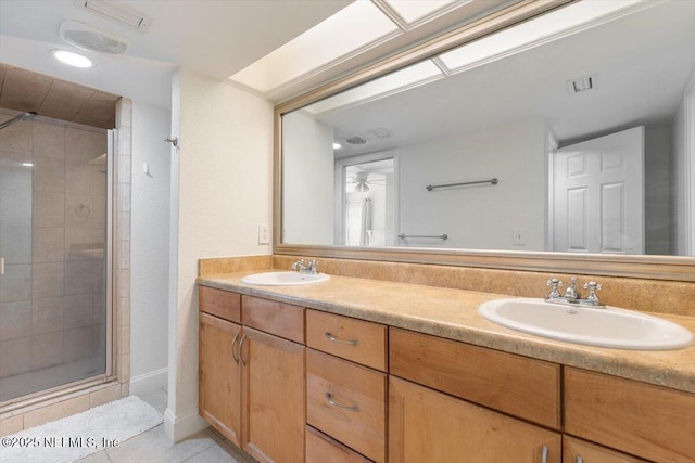 full bathroom featuring a sink, double vanity, a shower stall, and tile patterned floors