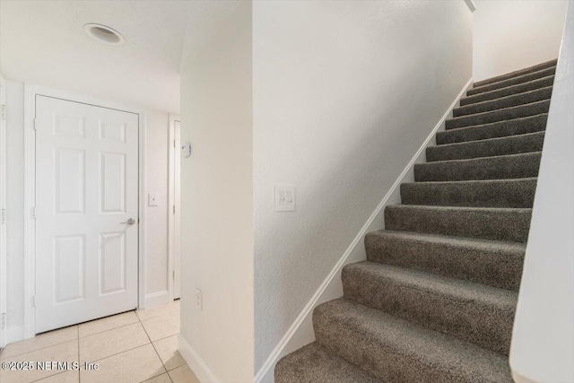 stairs featuring tile patterned floors and baseboards